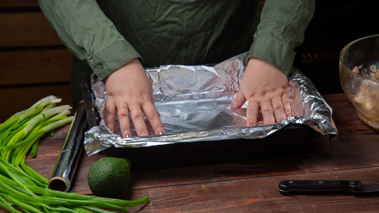 woman's hands line baking foil on a baking sheet. Horizontal photo.
