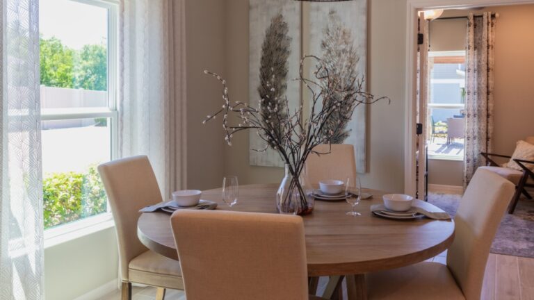 Cozy breakfast nook with round table and four upholstered chairs next to window, hanging pendant light and copy space