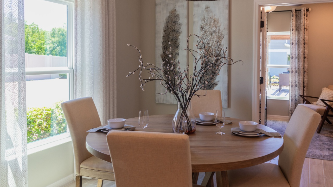 Cozy breakfast nook with round table and four upholstered chairs next to window, hanging pendant light and copy space