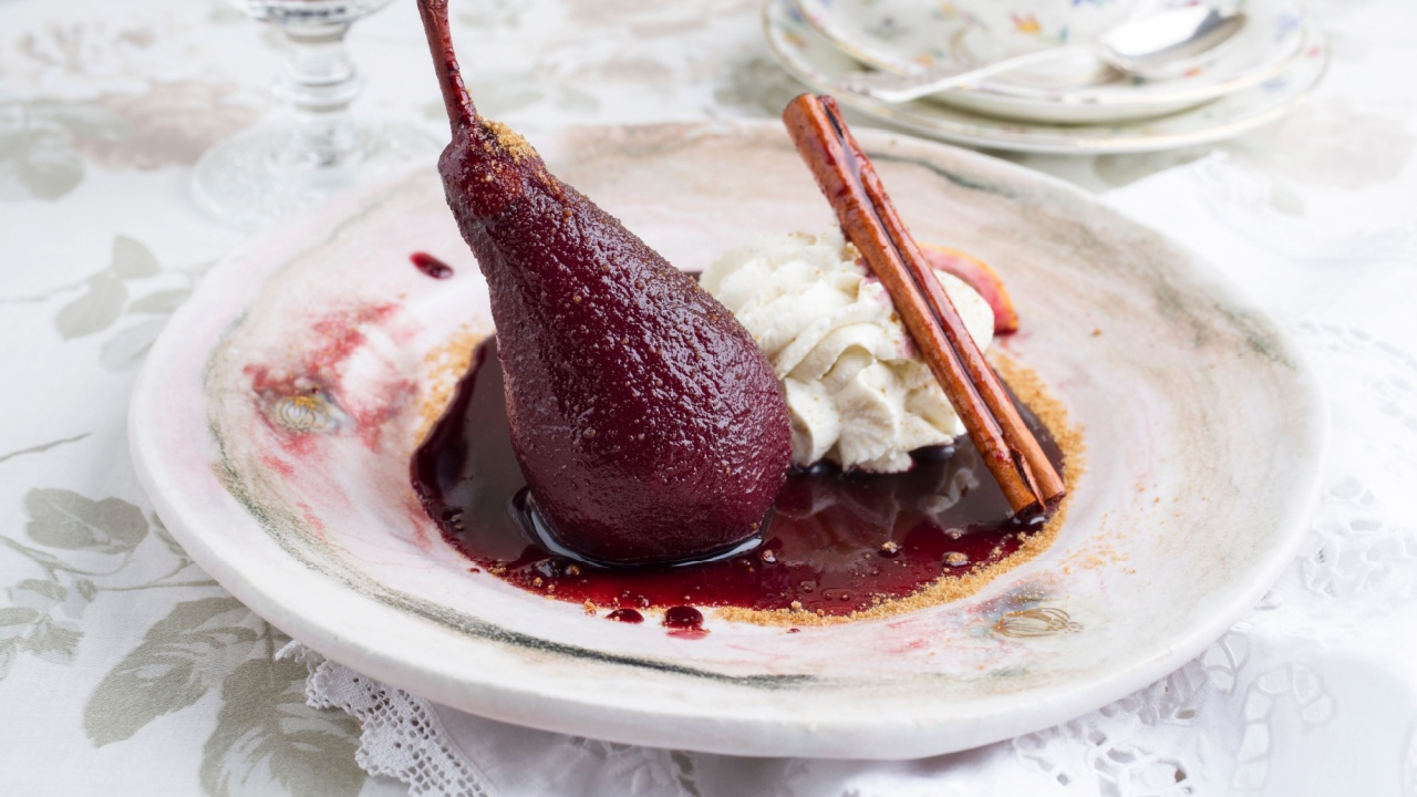 Traditional poarched pear in red wine sauce offered as close-up on a design plate