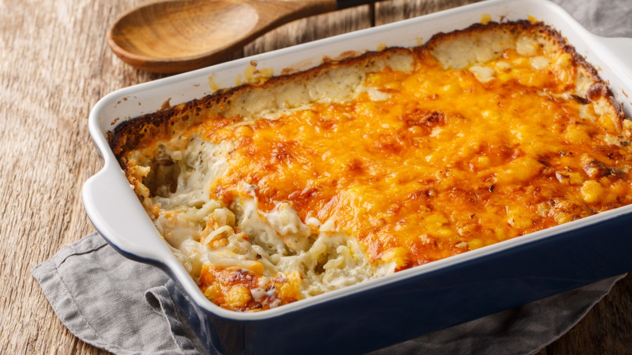 &Ntilde;lassic Southern hashbrown casserole is made with sour cream, Cheddar cheese and condensed soup closeup in the baking dish on the wooden table. Horizontal