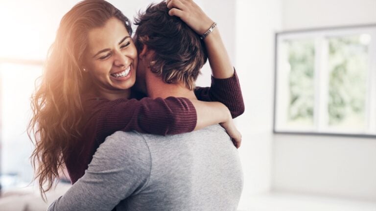 Couple, woman hug and laughing in home kitchen with love, bonding and smile together with joy. Embrace, romance and happy people with marriage with care, trust and commitment in house with fun joke