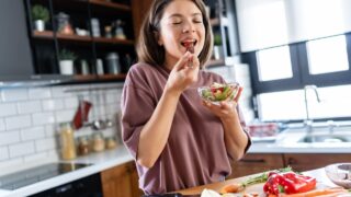 A young pretty cheerful woman is eating a salad. Healthy eating