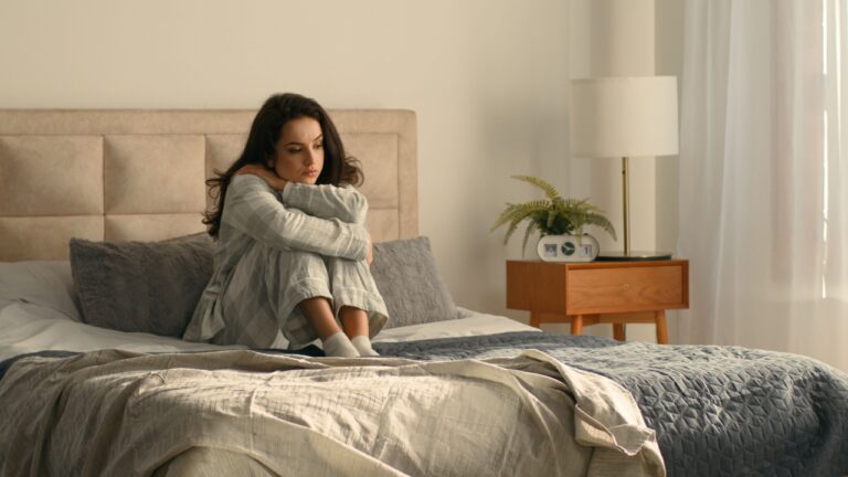 Woman hugging herself bed bedroom girl female hotel looking window rest relax calmness tranquility accommodation insurance wake up weekend cozy morning wellbeing daydream peaceful apartment domestic