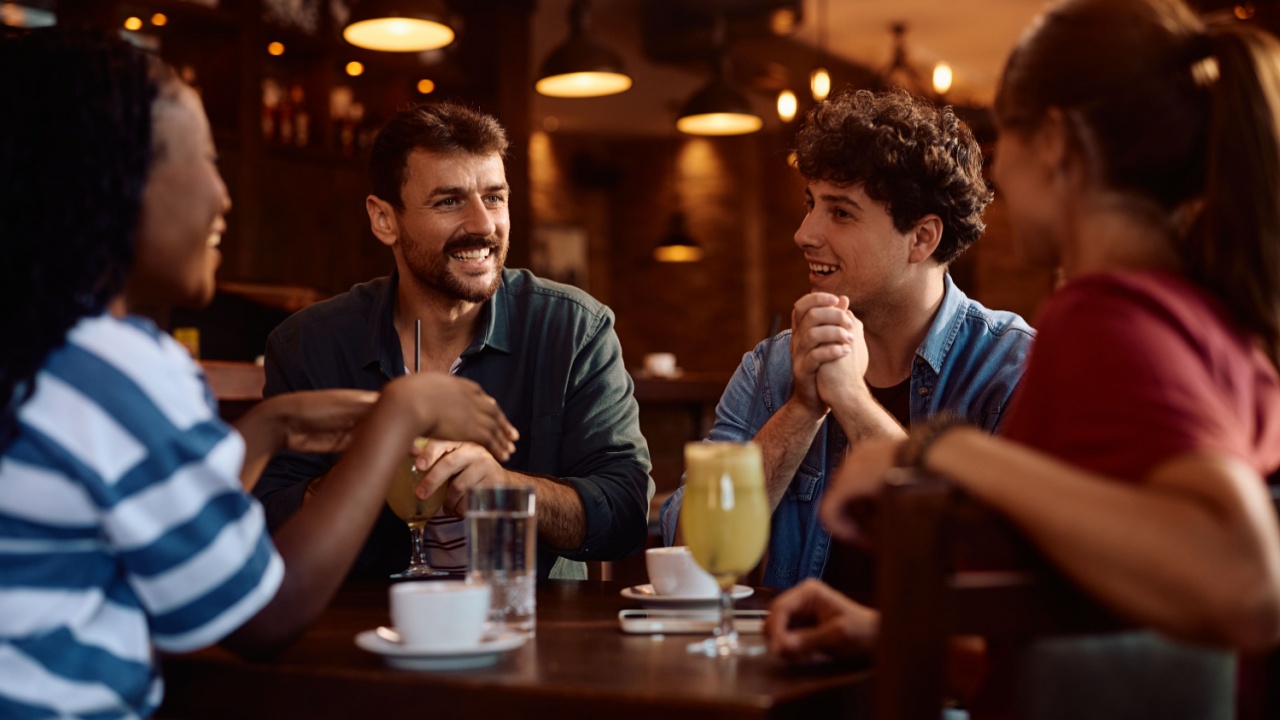 Group of happy friends communicating while gathering in a pub.