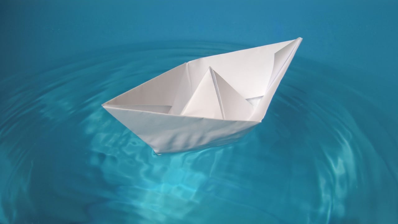 toy paper boat floating on blue water