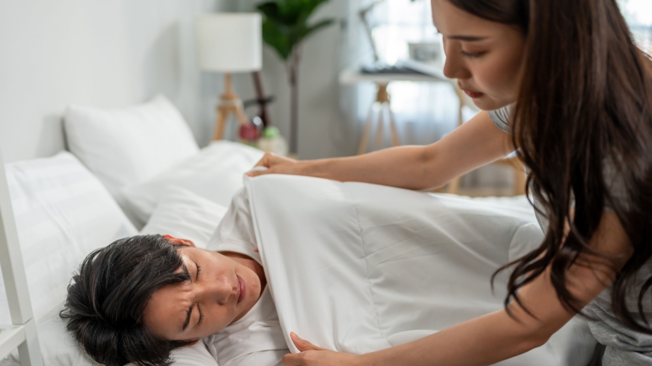 Asian young wife put blanket on sick husband with fever sleeping on bed. Attractive beautiful woman take care and support her sleeping boyfriend lying down in bedroom to rest for health care in house.