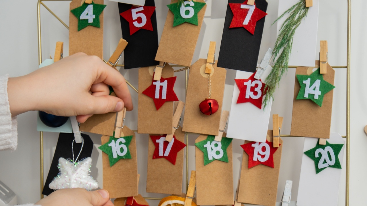 Number on craft paper notes with tasks before Christmas holidays. Female making kraft paper for handmade advent calendar Made with your own hands step by step DIY