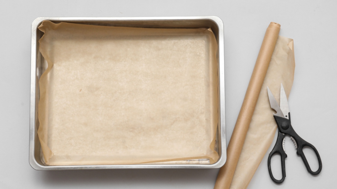 Empty baking tray, parchment paper and scissors on grey background