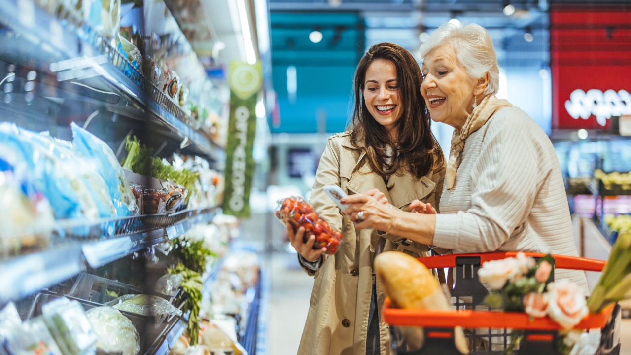 A joyful senior woman and young woman shopping for fresh groceries together in a supermarket, enjoying quality time and bonding while choosing produce and essentials.