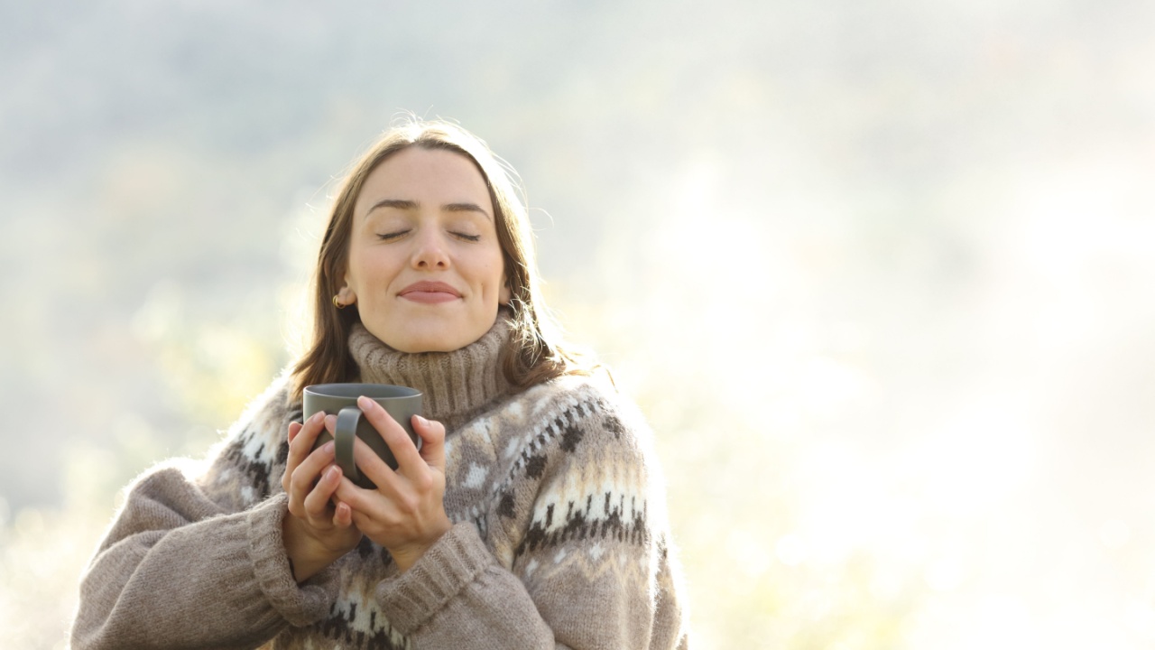Satisfied woman drinking and relaxing in winter closing ayes in a park