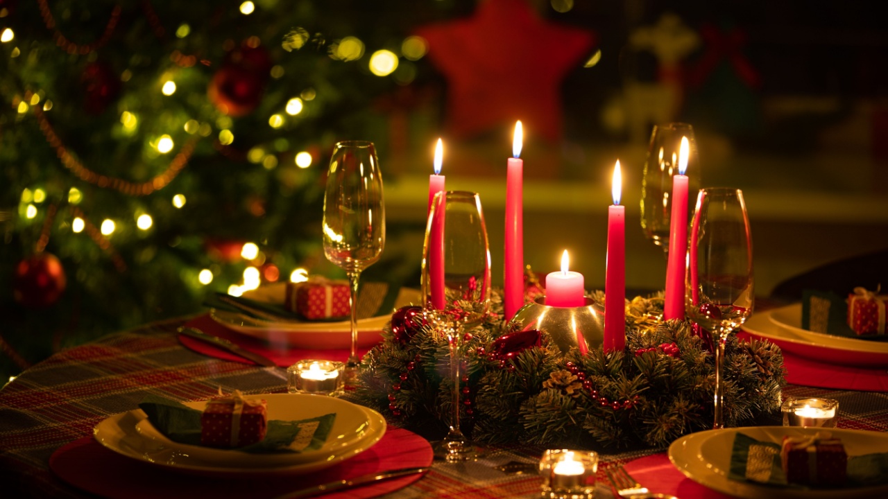 beautifully decorated Christmas table with candles and glasses near the Christmas tree