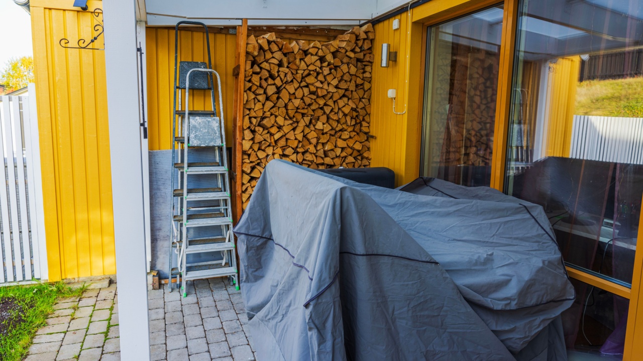 Winter preparation at villa with stacked firewood and covered outdoor furniture. Sweden.