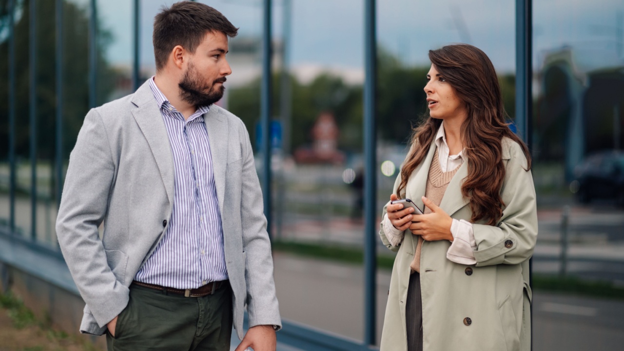 Stylish business people having a serious conversation while walking outside a modern office building, embodying corporate teamwork in an urban setting