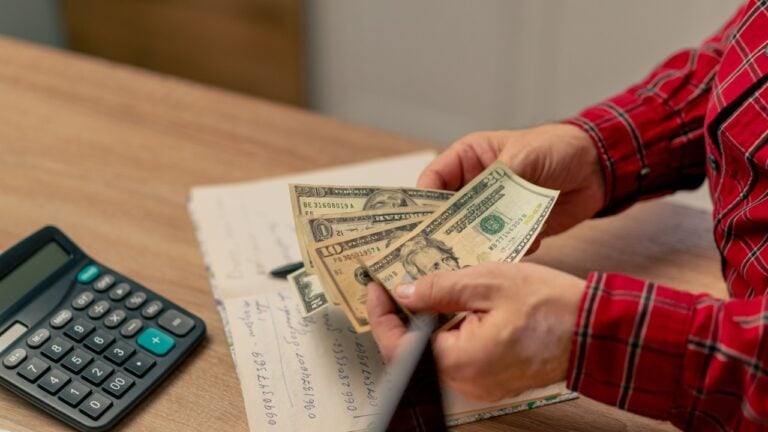 close-up in bright kitchen hands with American bills calculator payment receipts calculator hard pension utilities