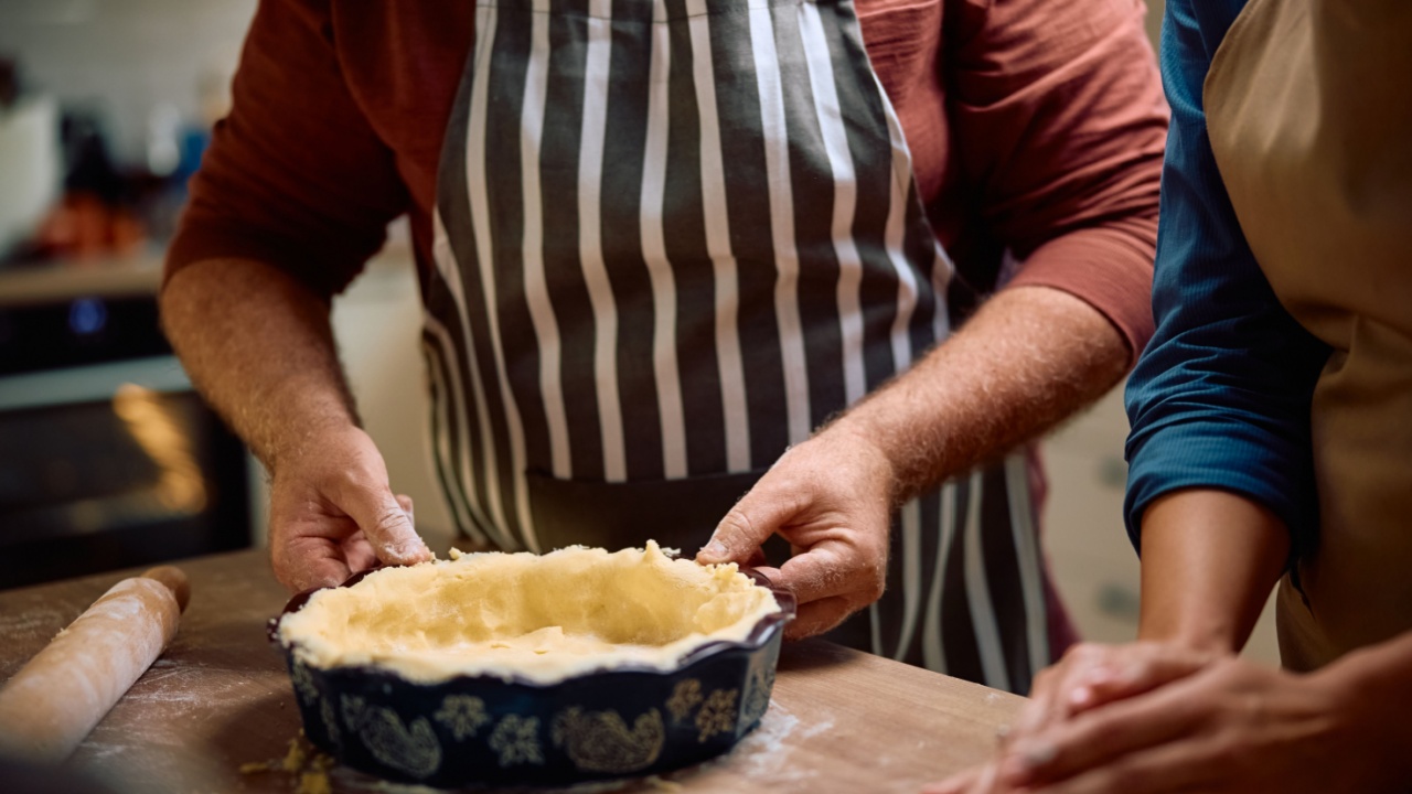 Close up of man preparing butter pie crust while baking at home.