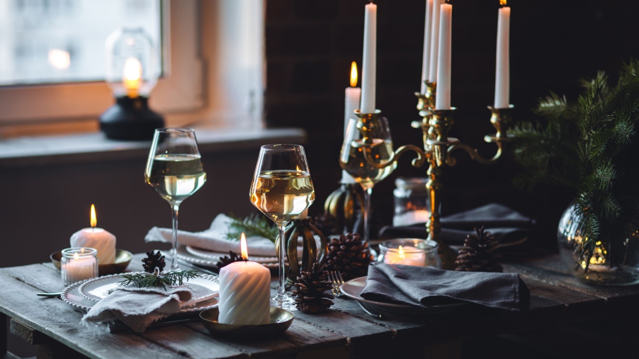 Rustic Scandinavian style zero waste eco-friendly dinner table decor for Christmas or new year family celebration. Wooden table, natural elements like pine cones, fir tree branches, candles