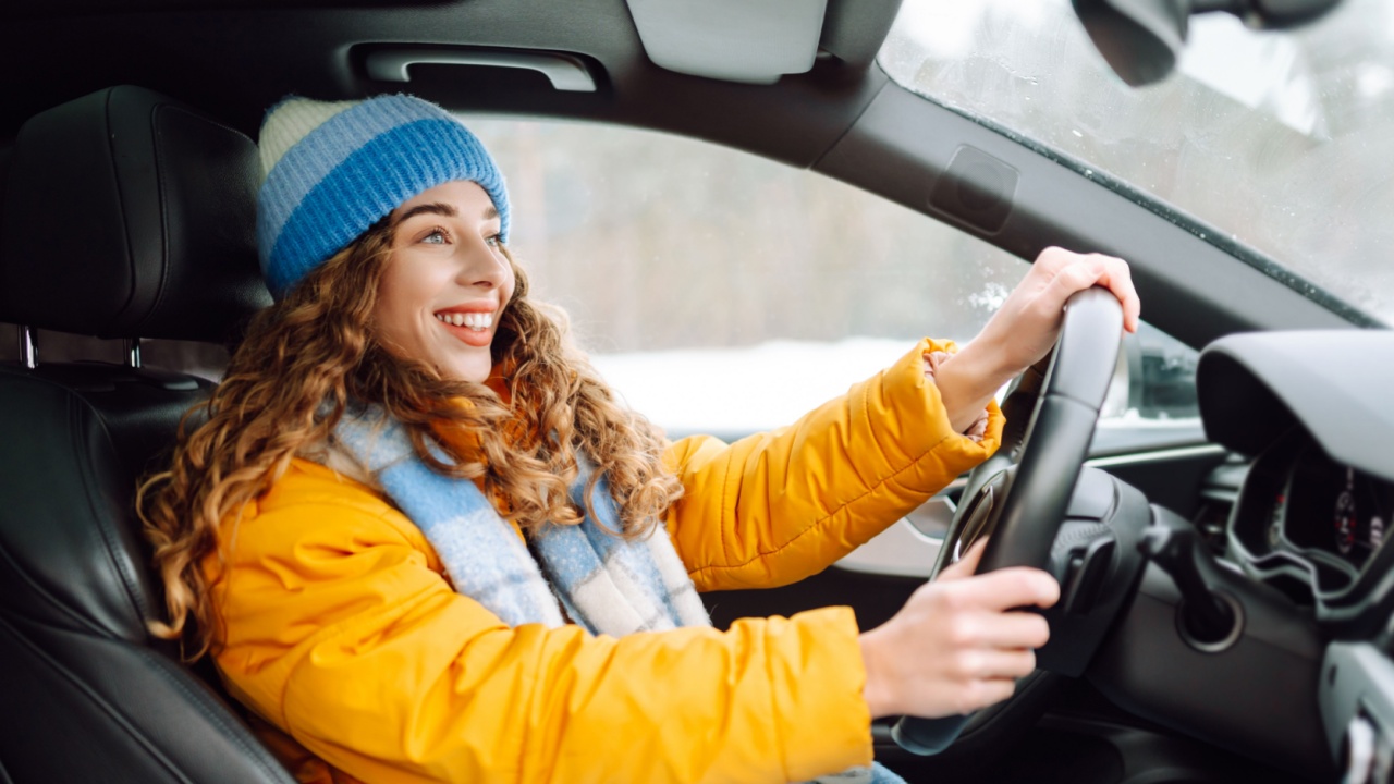Young woman driving car on winter highway during day time. The concept of transport, lifestyle. Winter holidays.