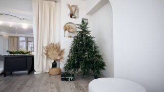 Rustic white Christmas scene, ornaments and wood trees. Stylish decorated christmas tree with glass transperent decor and modern decor. Modern christmas scandinavian living room.