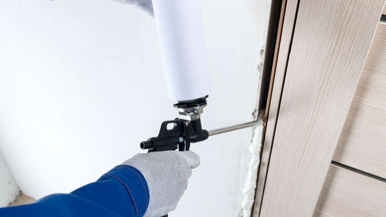 a master in gloves seals a gap between a wall and a door frame with mounting foam