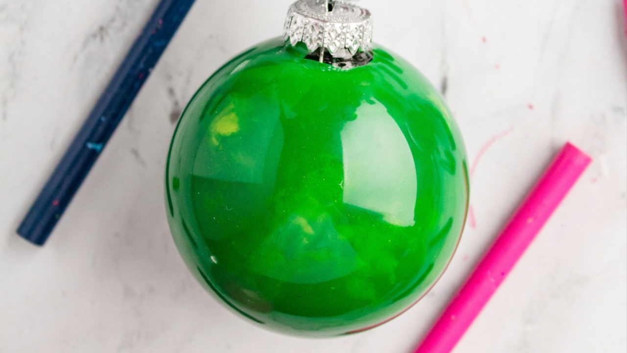 Green glossy ornament surrounded by colorful crayons