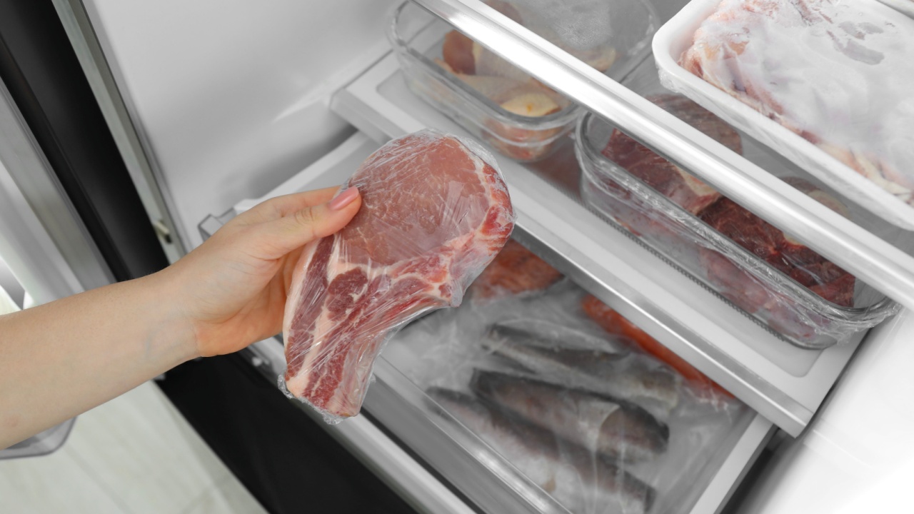 Woman taking frozen pork steak out of fridge, closeup