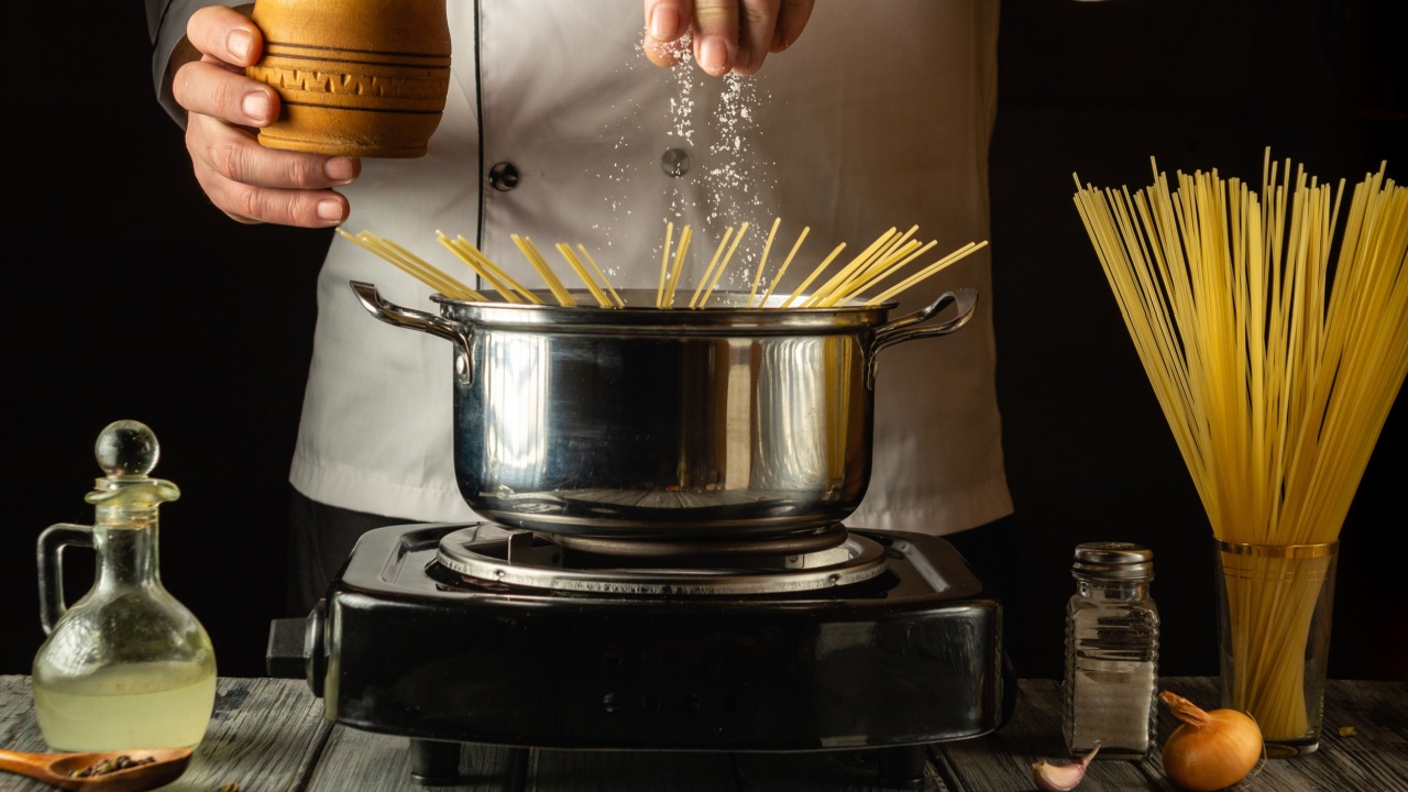 A chef expertly sprinkles salt over boiling pasta in a pot, surrounded by fresh ingredients and utensils. The warm kitchen glow enhances the culinary experience, inviting flavor exploration.