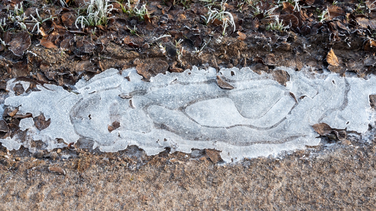 A small icy puddle on a dirt road on a cold winter day