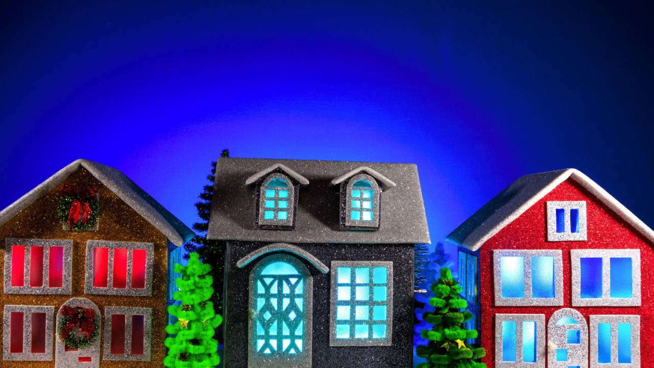 Between the brown, gray and red houses there are two green fir trees