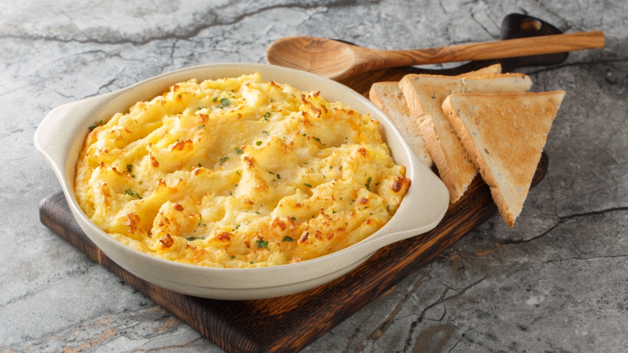 Golden baked mashed potatoes with cheddar and parmesan cheese, cream, butter and herbs close-up in a baking dish on the table. Horizontal