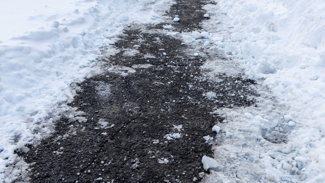 Sidewalk covered with salt and melting snow. Road for pedestrians in winter.