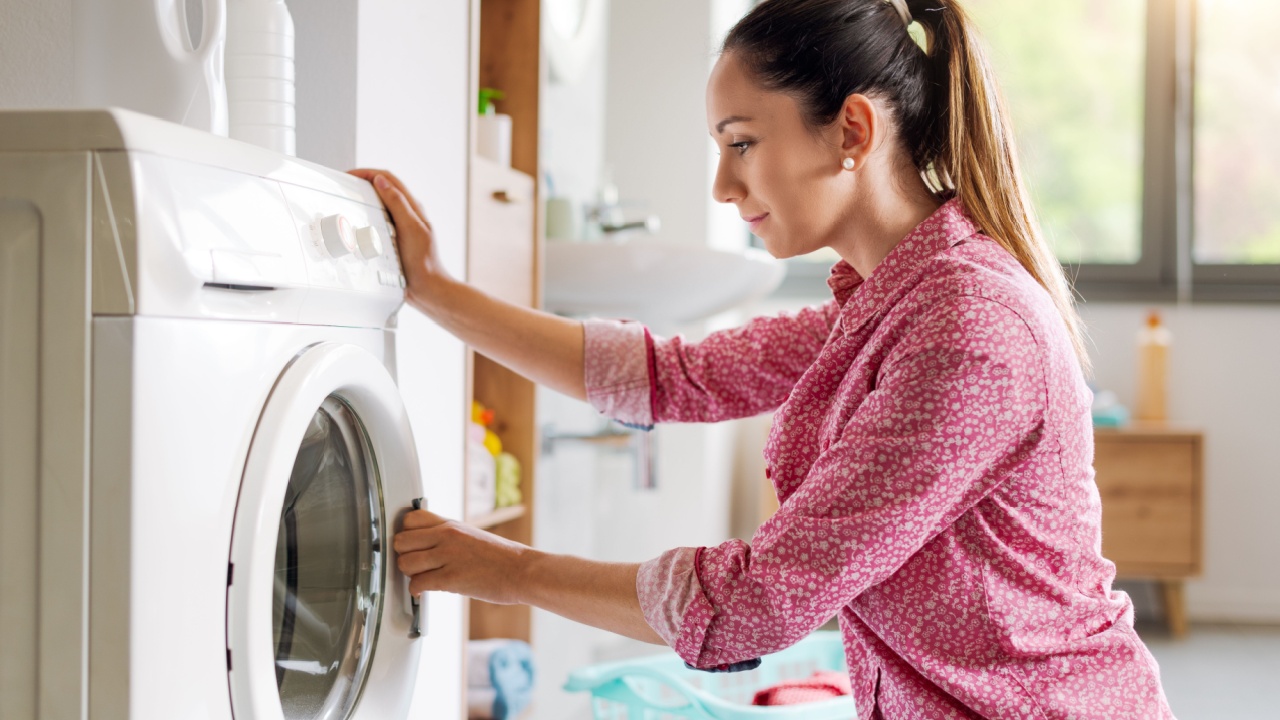 Woman doing laundry, she is closing the washing machine door