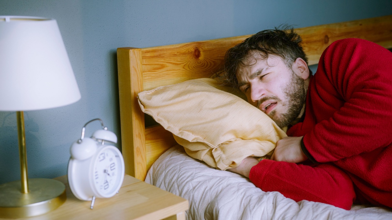 Young man Struggling to Wake Up &ndash; Looking Snooze on Alarm Clock