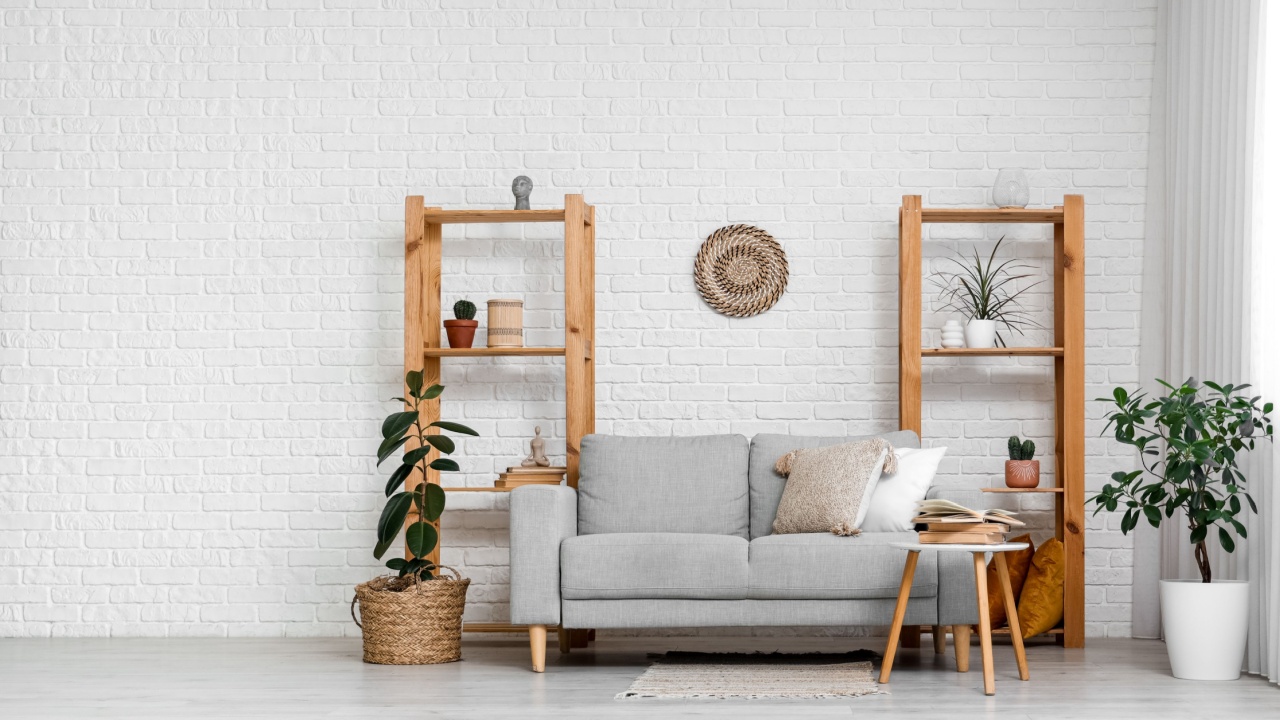 Wooden shelving units and sofa near white brick wall in interior of living room
