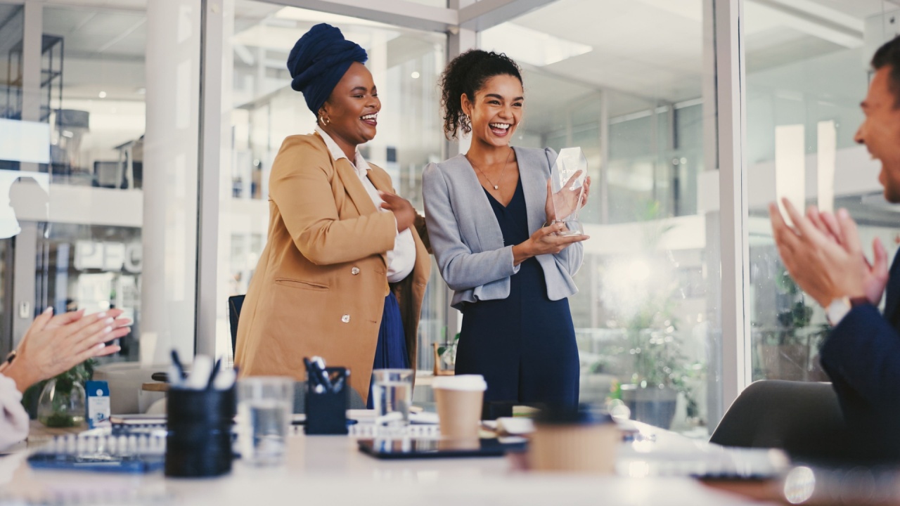 Business people, celebration and woman with trophy, smile and applause for recognition. Person, employees and consultant in office, kpi target and goals with thank you, award ceremony and achievement