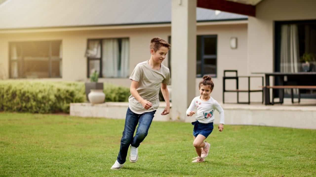 Children, running and playful game in backyard with energy, fun chase and race for bonding together. Kids, boy and girl with movement for exploring activity, creative adventure and childhood at house