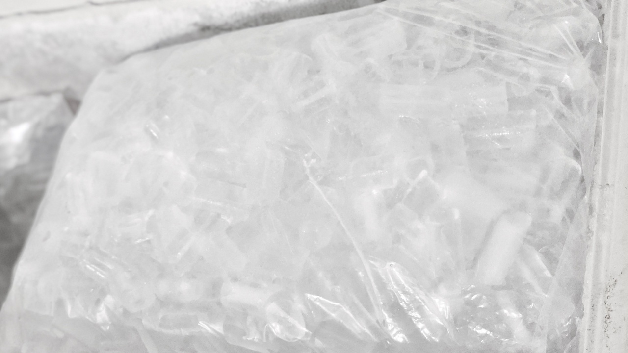A close-up view of cylindrical ice cubes inside a plastic bag stored in a freezer. The ice is ready for use in beverages.