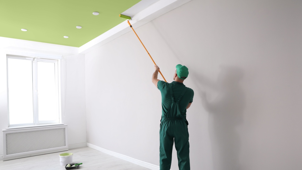 Man painting ceiling with green dye indoors