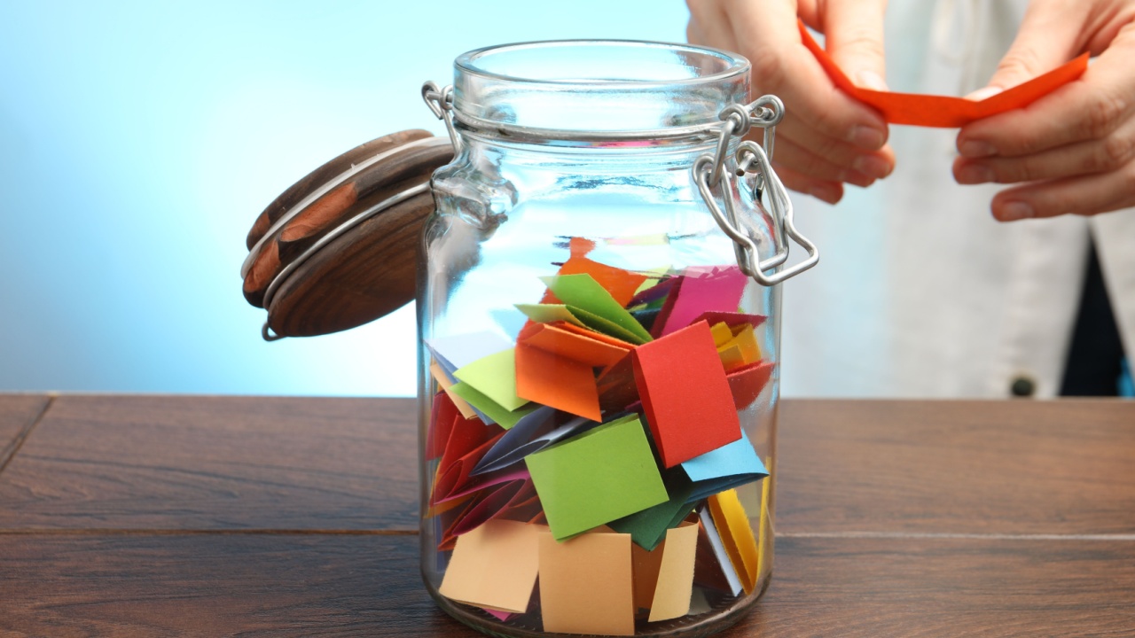Woman taking paper with message out of jar at wooden table, closeup