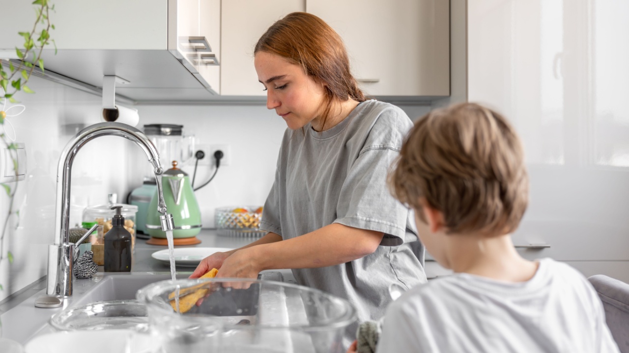 Teenage girl washing dishes. Washing dishes in the kitchen. Housework.