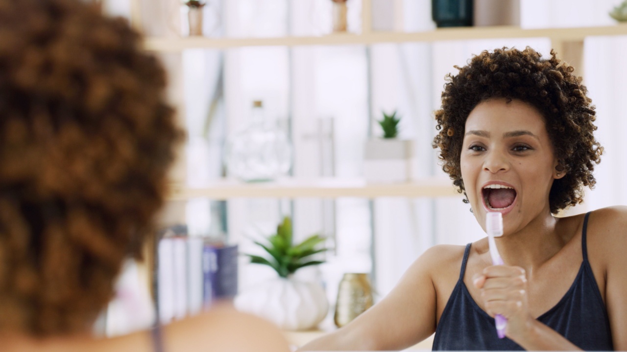 Mirror, singing and toothbrush with woman in bathroom of home for energy, fun or hygiene. Brushing teeth, cleaning and oral care with reflection of African person in apartment for dental satisfaction