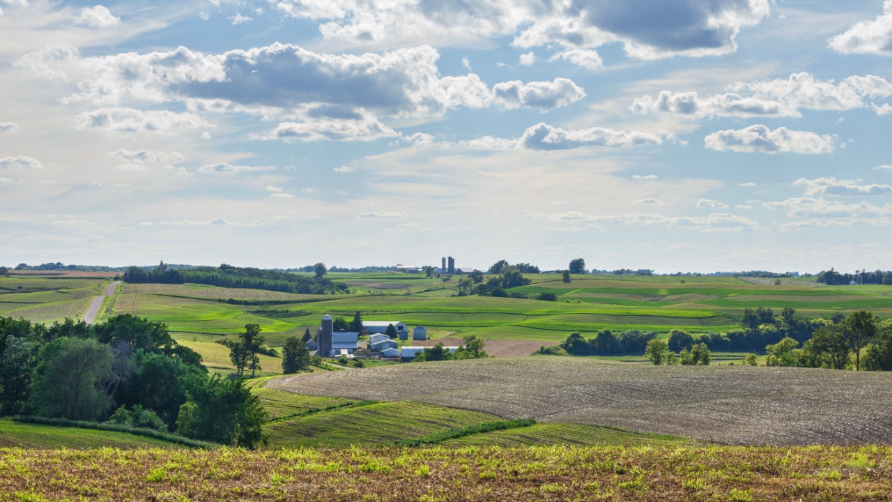 Iowa farms and fields on rolling hills under a beautiful cloudscape on a sunny summer afternoon