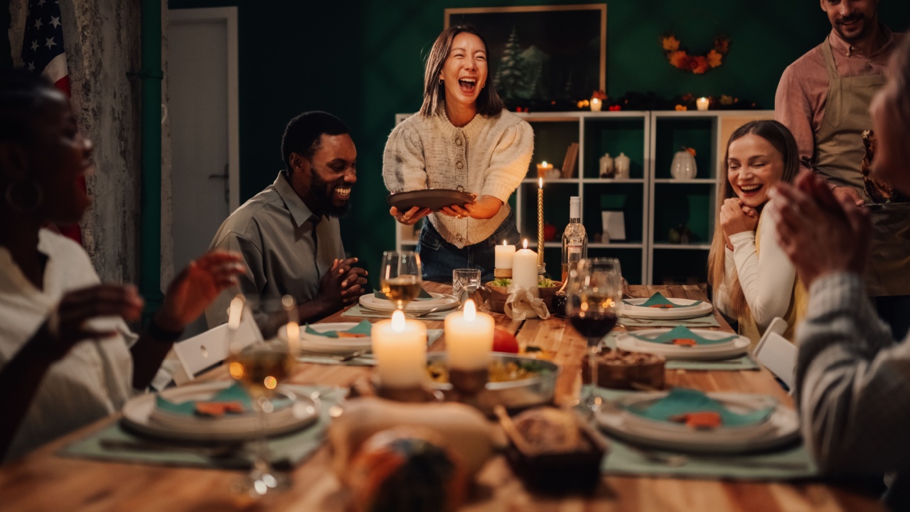 Happy multi ethnic friends laughing and enjoying a festive thanksgiving or christmas dinner together at home, creating joyful memories