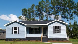 Powder blue low-income single-story home with porch.