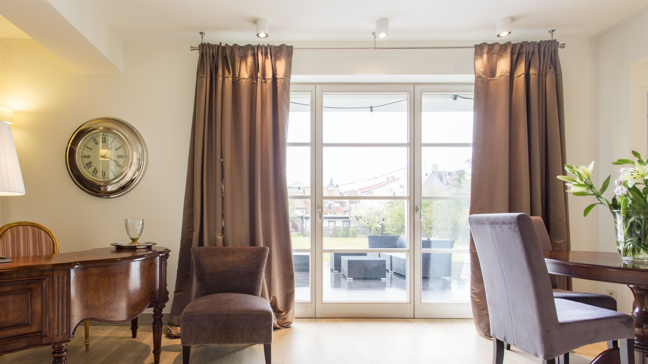 dark grey curtains hanging from a curtain rod in a room. made of a heavy, possibly light-blocking material. silver grommets from a black curtain rod that is mounted to the wall.