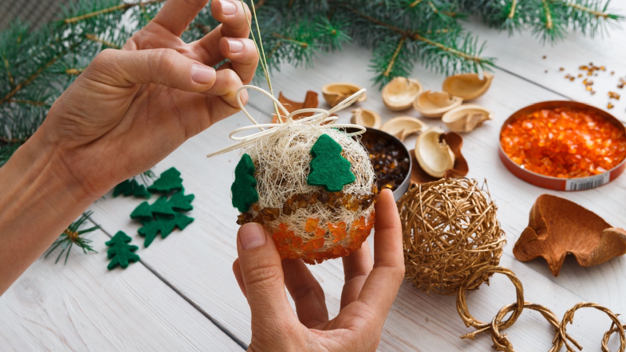 Creative diy craft hobby. Making handmade craft christmas ornaments and balls with felt spruce tree. Woman's leisure, holiday decorations. Closeup of female hands at white wood background