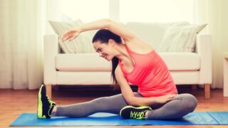 Smiling teenage girl streching on floor at home