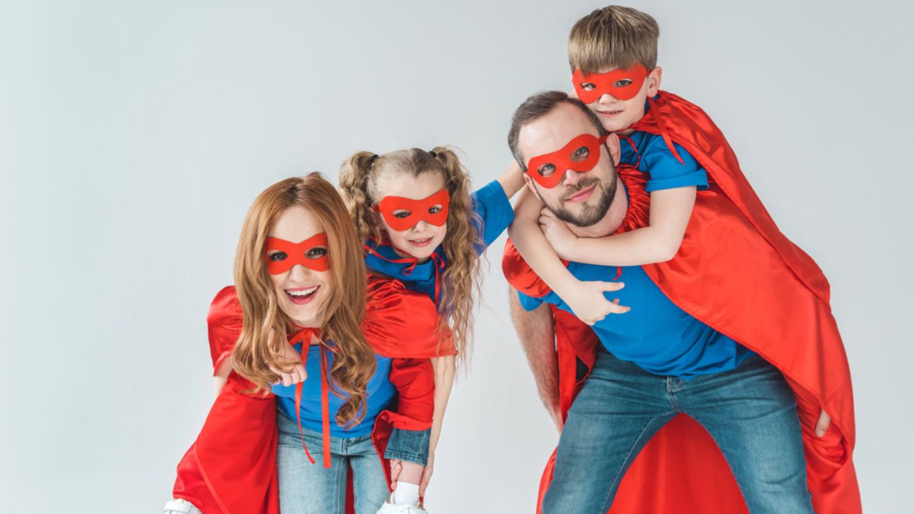 Super parents piggybacking kids pretending to be superheroes isolated on grey