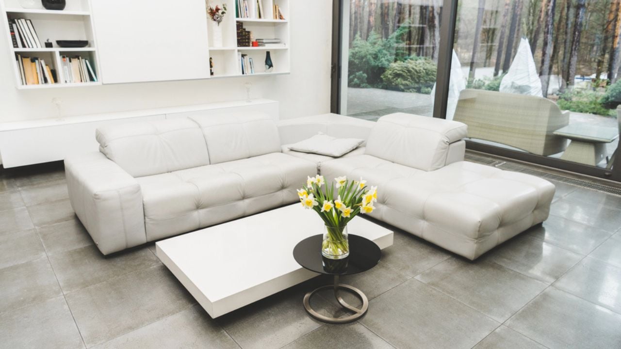 View of empty living room with white sofa and bouquet of flowers on coffee table