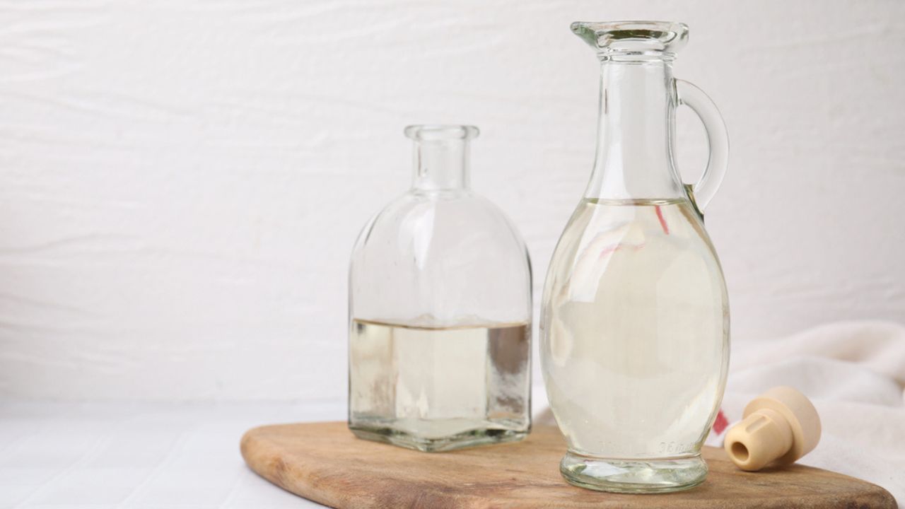 Vinegar in glass jug and bottle on white table